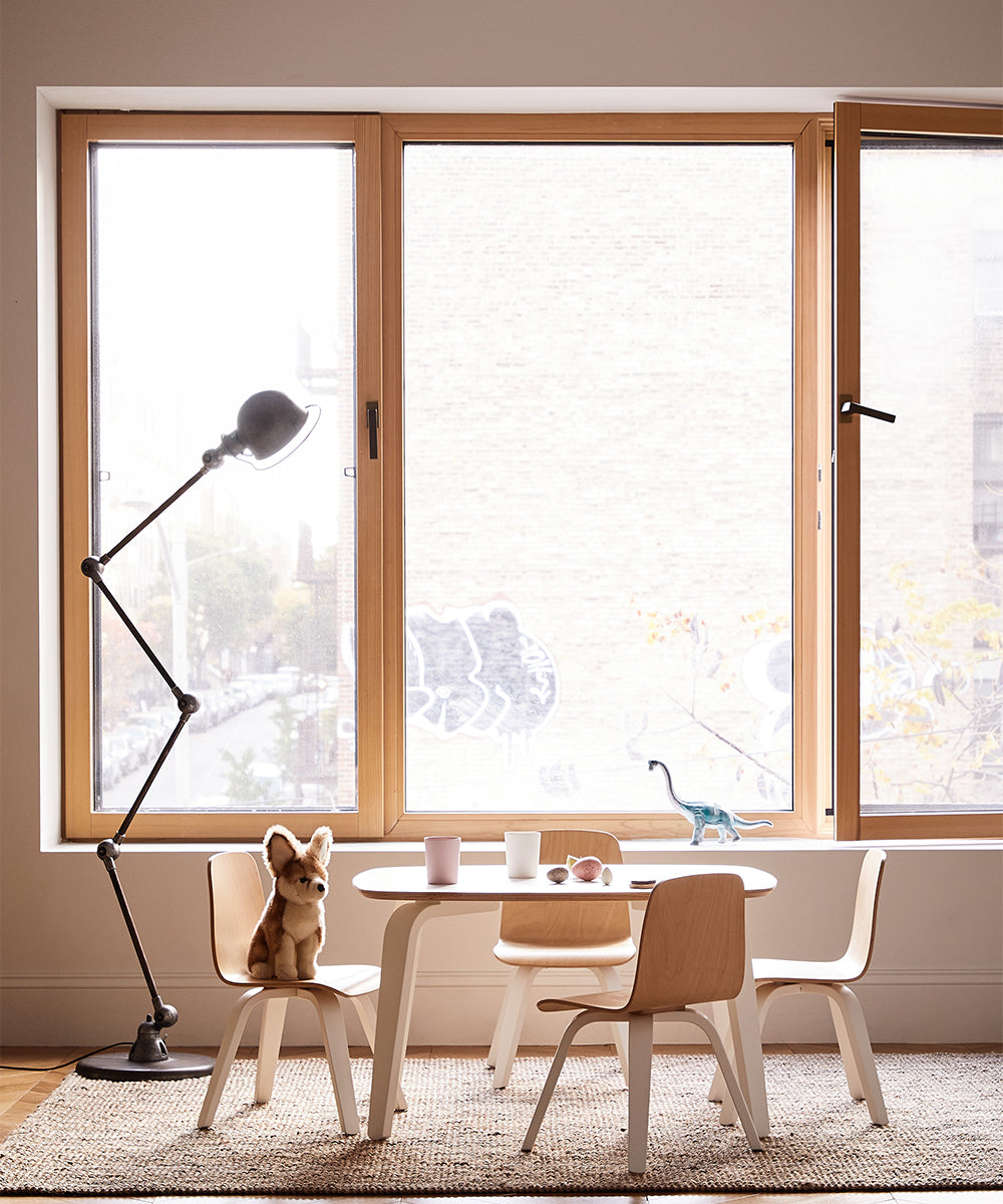 Childrens play area with a Play Chair set, a toy fox, dinosaur figurine, and cups by a large window, illuminated by a nearby floor lamp.