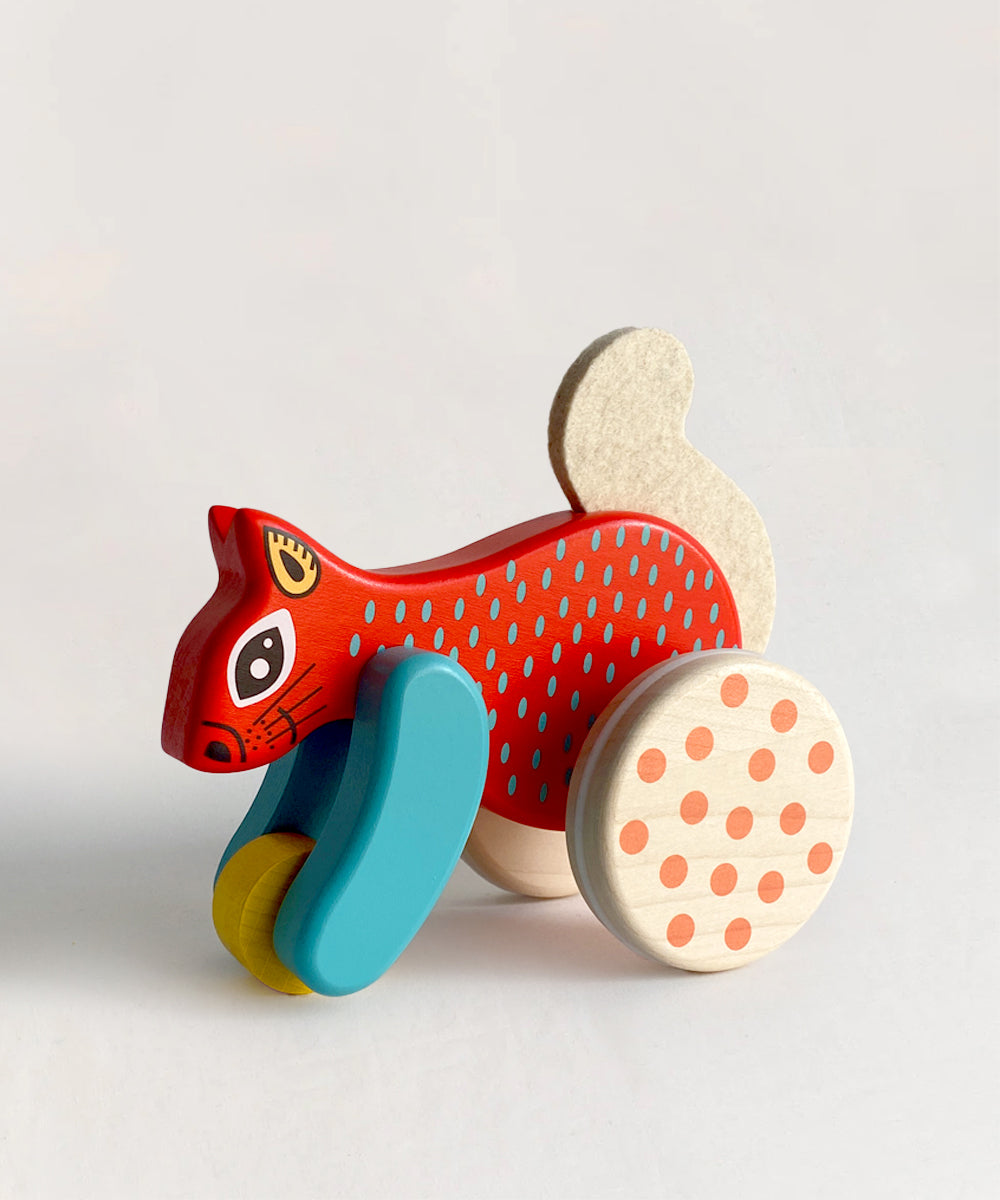 Le Squirrel Toy: A colorful wooden squirrel with blue, yellow, and polka-dotted wheels on a plain light background.