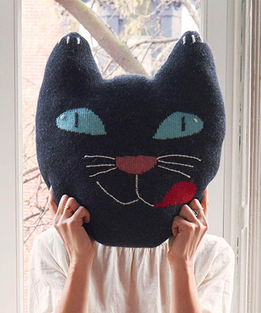 Someone holds the Black Cat Pillow in front of their face near a window.
