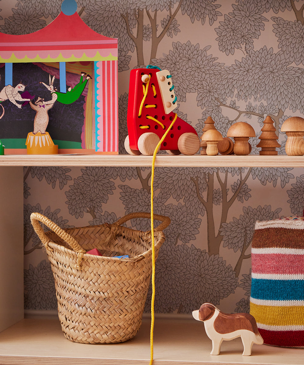 Children's shelf with Le Lacing Shoe, wooden dog, basket, stack of mushrooms, and colorful striped blanket.