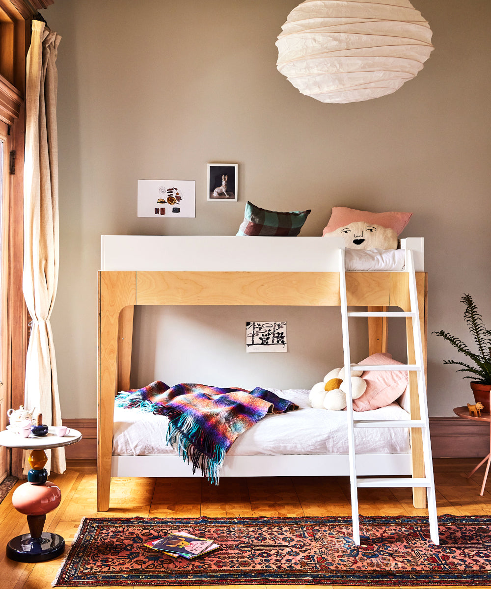 Kids' room featuring a bunk bed, Daisy Pillow, colorful bedding, toys, artwork, plants, and a hanging paper lantern.