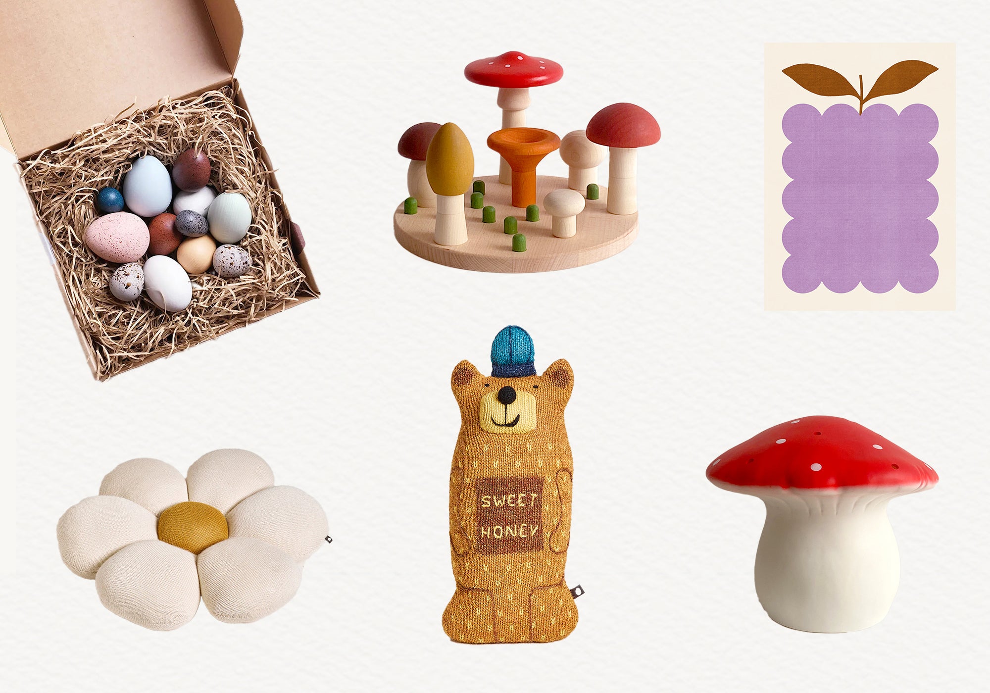 A collection of childrens toys: a box of colorful eggs, wooden mushrooms, purple print, flower cushion, bear plush with Sweet Honey, and a red-capped mushroom toy.