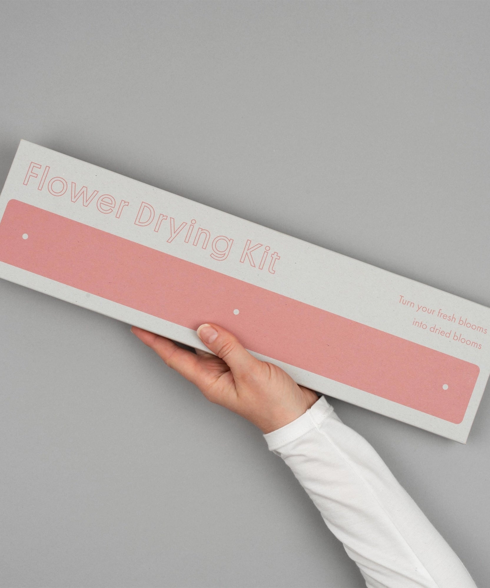 A hand holds the Flower Drying Kit box against a plain grey background.