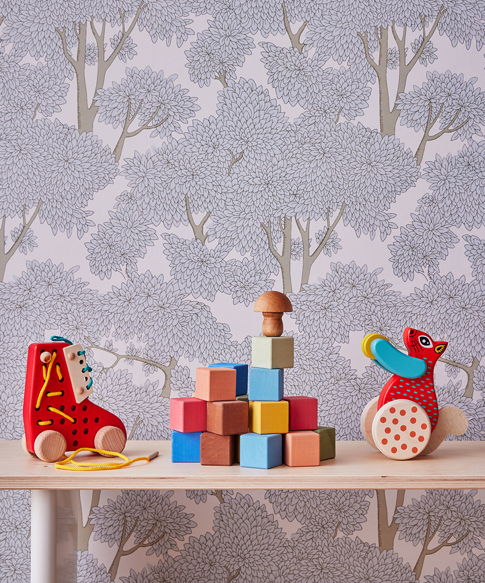 Le Squirrel Toy displayed with colorful blocks on a table, set against a floral wallpaper background.