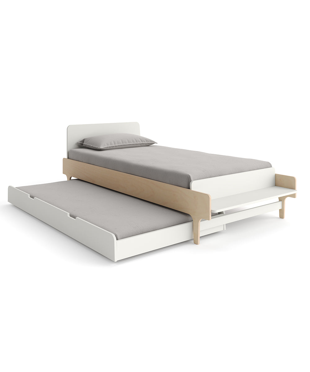 A white twin bed with a wooden frame and pull-out trundle topped with gray bedding and a pillow.