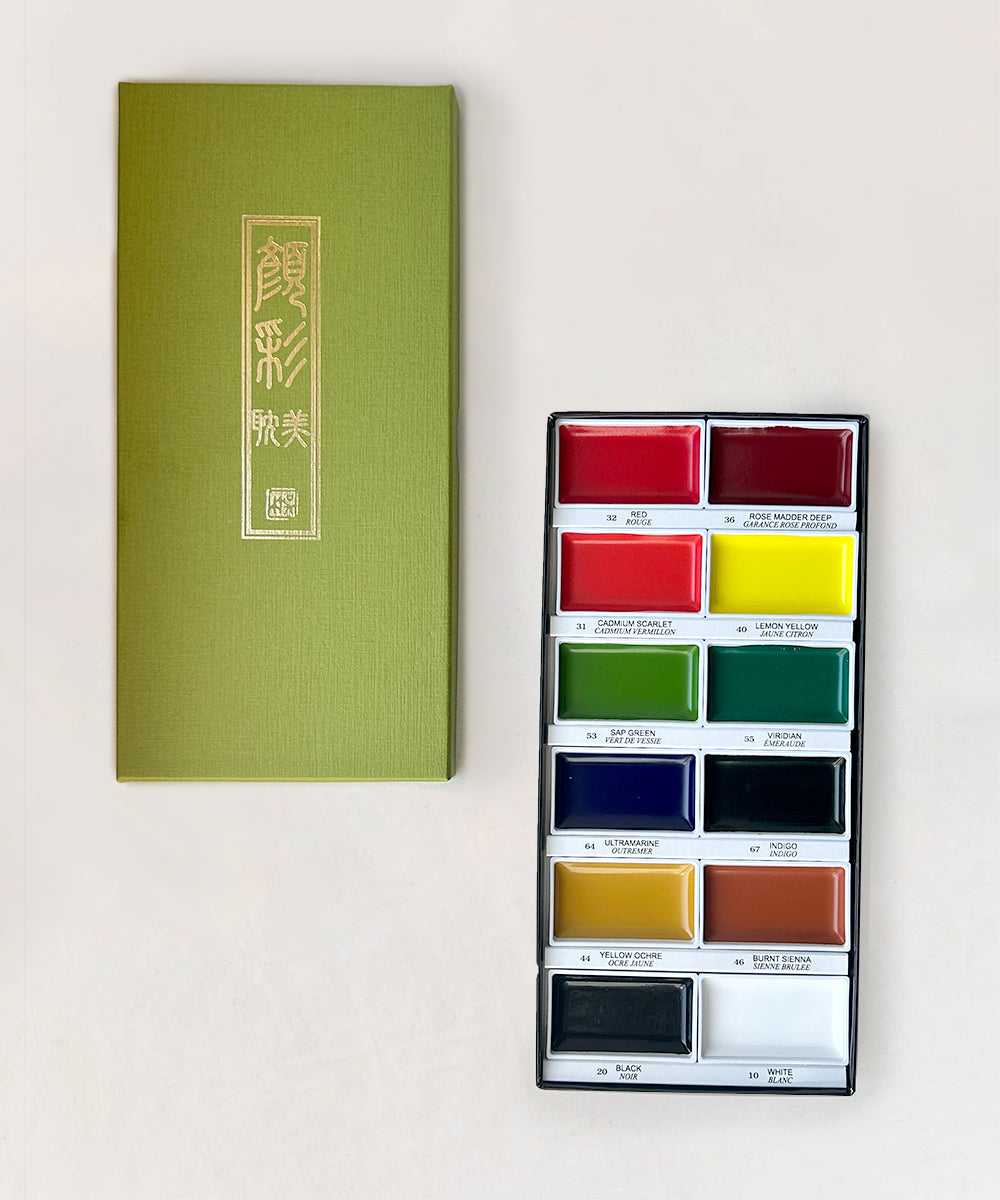 Green box beside the Gansai Tambi Watercolor Paint Set - Primary Colors, showcasing twelve vibrant hues including red, yellow, and blue.