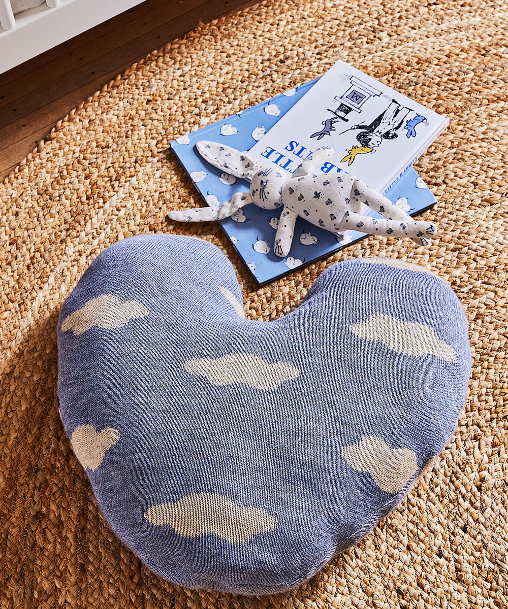 Heart Cloud Pillow, plush bunny toy, and books on a woven rug.
