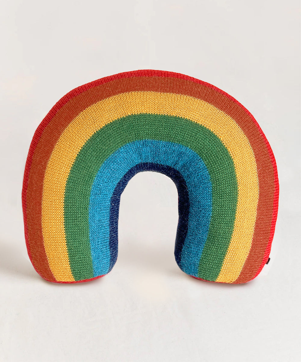 The Rainbow Pillow is a plush cushion shaped like a rainbow with red, orange, yellow, green, blue, and navy stripes.